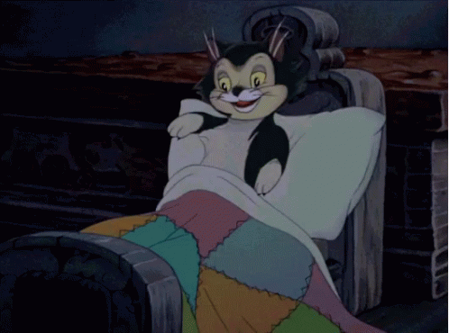 A Cartoon Character Is Laying On A Bed With A Colorful Quilt GIF