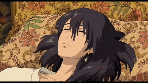 A Cartoon Character Is Laying On A Couch With A Floral Blanket GIF
