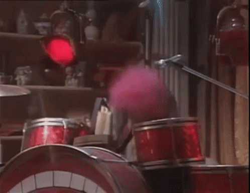 A Cartoon Character Is Playing Drums In A Room With A Red Light Behind Them . GIF