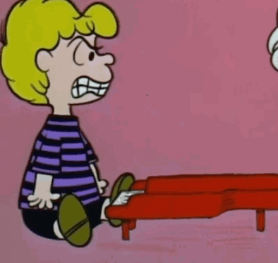 a cartoon character is sitting in front of a red piano and making a funny face .
