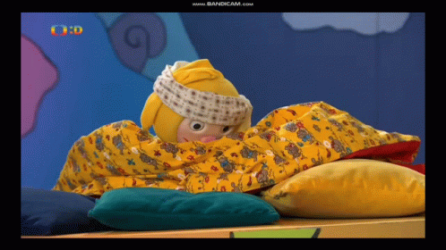 A Cartoon Character Is Wrapped In A Yellow Blanket On A Bed GIF