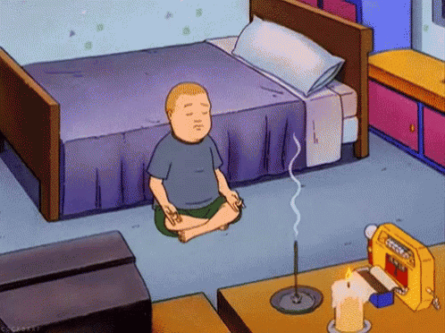 A Cartoon Character Sits In A Lotus Position In Front Of A Bed GIF
