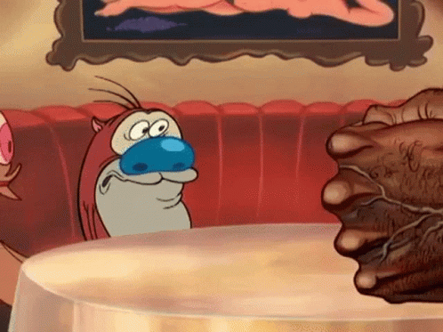 A Cartoon Character With A Blue Nose Is Sitting At A Table With A Fist . GIF