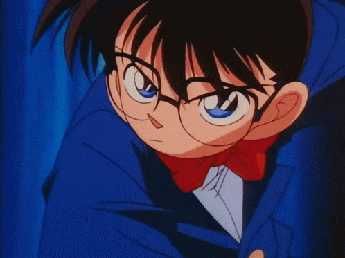 A Cartoon Character With Glasses And A Blue Jacket Is Standing In Front Of A Blue Curtain GIF