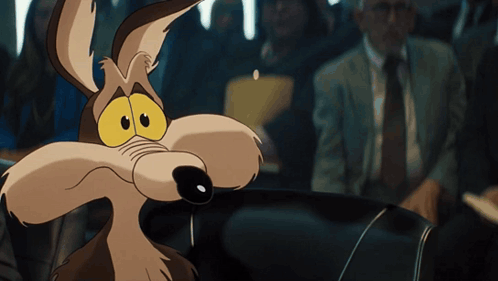 a cartoon coyote is sitting in a car looking at the camera