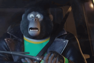 A Cartoon Gorilla Wearing A Leather Jacket And A Green Shirt Is Driving A Car GIF