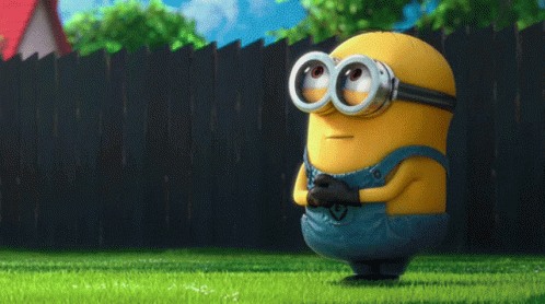 A Cartoon Minion Wearing Goggles And Overalls Stands In The Grass GIF