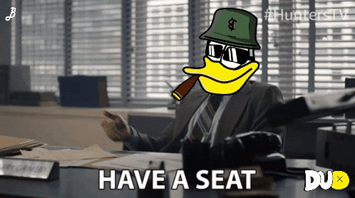 Man Sitting At Desk With Have A Seat Text GIF