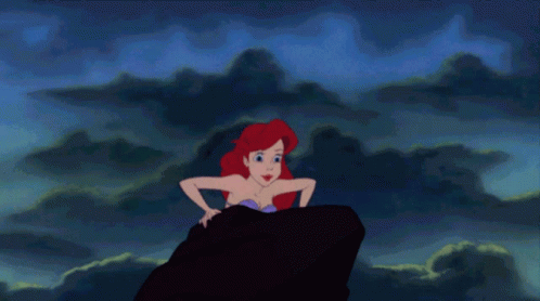 A Cartoon Of A Mermaid Sitting On A Rock In The Ocean GIF