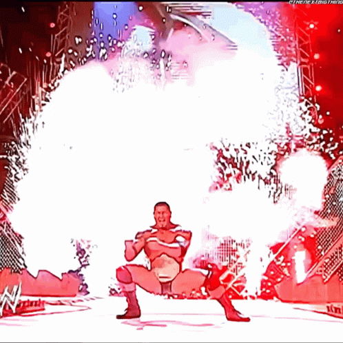 A Cartoon Of A Wrestler Standing In Front Of A Fireworks Display With The Letters W On The Bottom GIF