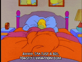 A Cartoon Of Homer Simpson Laying In Bed Saying Ahhh I 'M Just A Big Toasty Cinnamon Bun. GIF