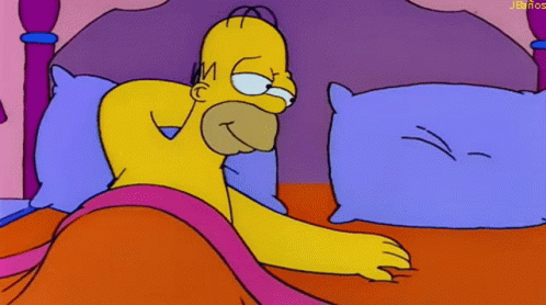 A Cartoon Of Homer Simpson Laying In Bed With A Purple Pillow GIF