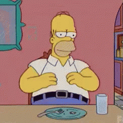 A Cartoon Of Homer Simpson Sitting At A Table GIF