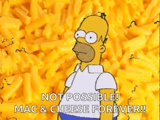 A Cartoon Of Homer Simpson Standing In Front Of A Pile Of Macaroni Cheese . GIF