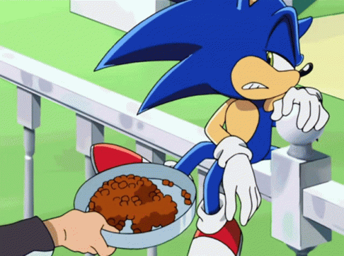 A Cartoon Of Sonic The Hedgehog With A Bowl Of Food In Front Of Him GIF