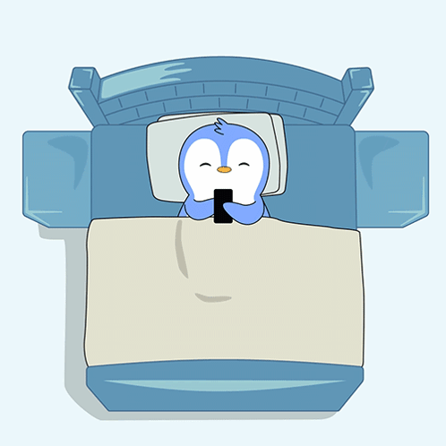 A Cartoon Penguin Is Sleeping In A Bed With A Cell Phone On The Blanket GIF
