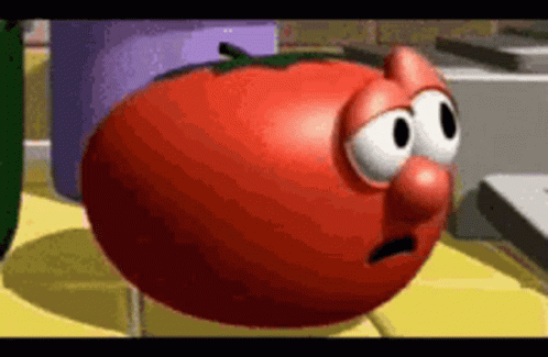 A Cartoon Tomato With Big Eyes And A Nose Is Standing On A Yellow Table . GIF