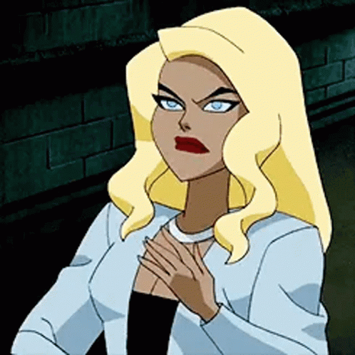 A Cartoon Woman With Blonde Hair And Blue Eyes Is Standing In Front Of A Brick Wall With Her Hands On Her Chest . GIF