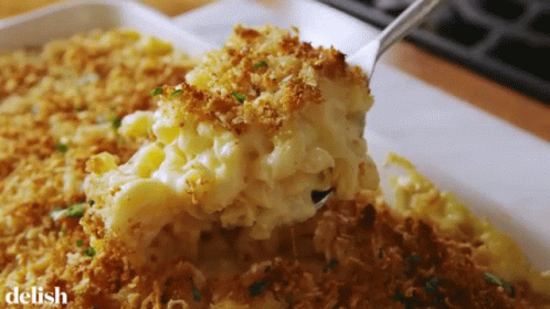 A Casserole Dish With Macaroni And Cheese And A Spoon In It GIF