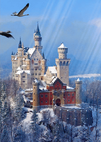 A Castle Surrounded By Snow And Trees With Birds Flying Overhead GIF