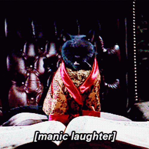 A Cat In A Robe Is Sitting On A Bed With The Words [ Manic Laughter ] Written Above It GIF
