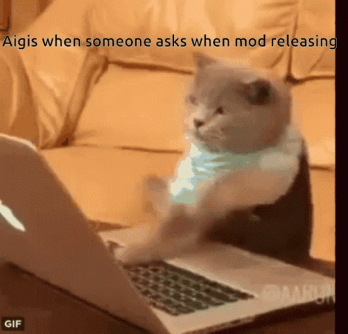 A Cat Is Sitting In Front Of A Laptop With The Caption " Aigis When Someone Asks When Mod Releasing " On The Bottom GIF