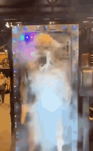 A Cat Is Standing In Front Of A Mirror With Lights On It . GIF
