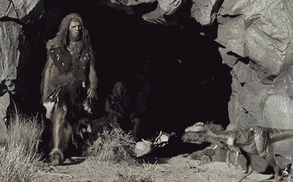 A Caveman Is Standing In Front Of A Cave GIF