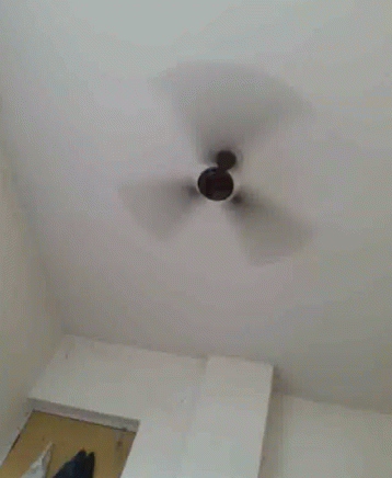 A Ceiling Fan Is Spinning In A Room . GIF