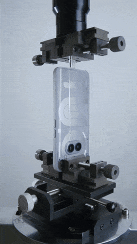 A Cell Phone Is Being Tested On A Machine With A Microscope In The Background GIF