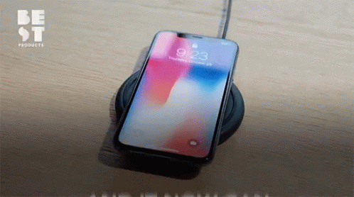 A Cell Phone Sitting On A Charger With The Time 9:23 On The Screen GIF
