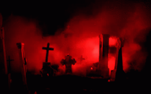 A Cemetery With Red Smoke Coming Out Of The Ground GIF