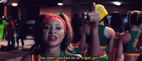 A Cheerleader Is Giving A Thumbs Up While Standing In Front Of A Crowd Of Cheerleaders . GIF