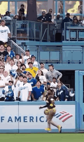 A Cheerleader Is Jumping In The Air At A Baseball Game While A Crowd Watches . GIF