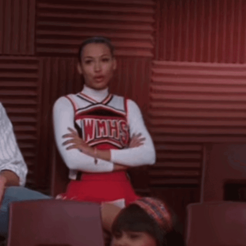 A Cheerleader Wearing A Wmhs Uniform Sits In A Chair With Her Arms Crossed GIF