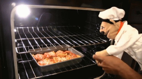A Chef Puppet Is Looking At A Pan Of Food In The Oven GIF