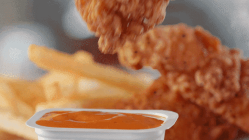 A Chicken Nugget Is Being Dipped Into A Container Of Sauce GIF