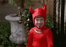 A Child In A Red Devil Costume Is Smiling . GIF