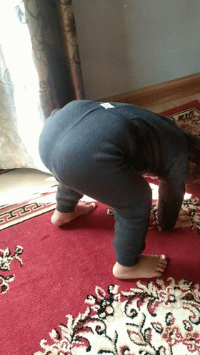 A Child Is Bending Over On A Red Rug GIF