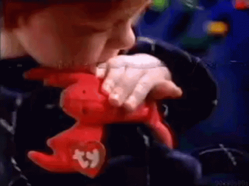 A Child Is Holding A Stuffed Animal With A Beanie On It . GIF