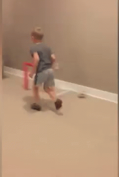 A Child Is Jumping In The Air Near A Basketball Hoop In A Room GIF