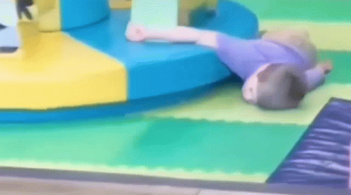 A Child Is Laying On The Floor In A Playground GIF
