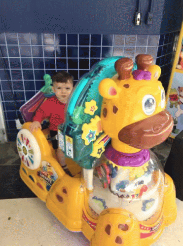 A Child Is Sitting On A Giraffe Rocker Toy GIF