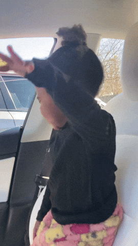 A Child Sitting In The Back Seat Of A Car With Her Arms Outstretched GIF