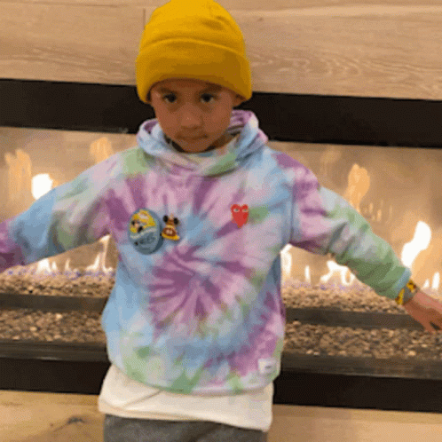 A Child Wearing A Tie Dye Sweatshirt And A Yellow Hat GIF