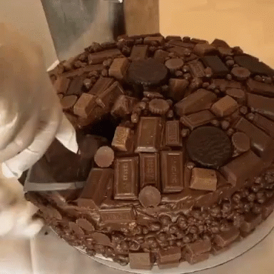 A Chocolate Cake Is Being Decorated With Hershey Candy Bars GIF