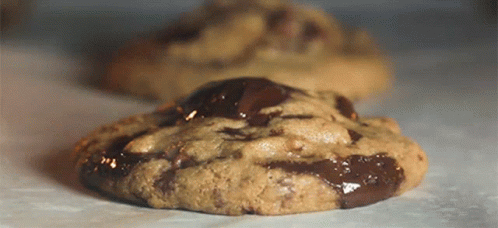 A Chocolate Chip Cookie Is Sitting On A Table GIF