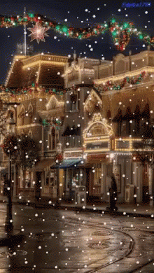 A Christmas Scene With Snow Falling In Front Of A Building GIF