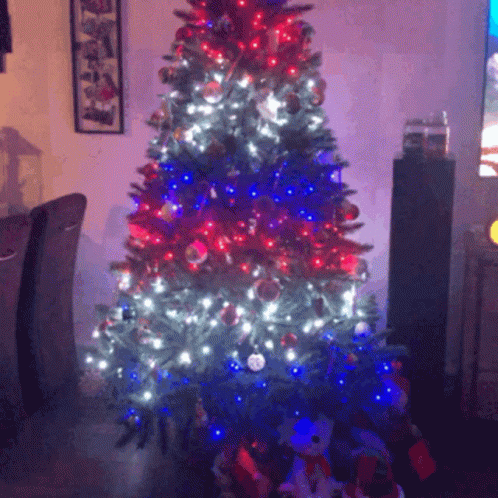 A Christmas Tree With Red White And Blue Lights And Decorations GIF