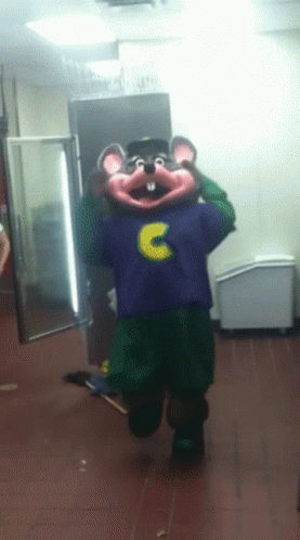 A Chuck E Cheese Mascot In A Purple Shirt With The Letter C On It GIF